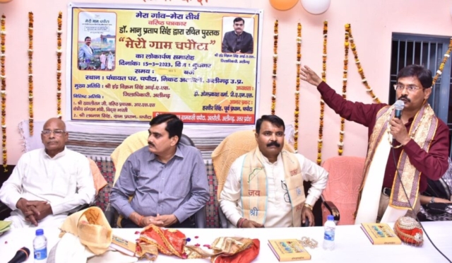 Author Dr. Bhanu Pratap Singh addresses the launch ceremony of the book 'Mera Gaam Chapouta' in village Chapouta, Aligarh. Seated on the stage from left are Dr. Om Prakash Verma, Indra Vikram Singh, IAS DM Aligarh, and RSS Pracharak Khayaliram ji.